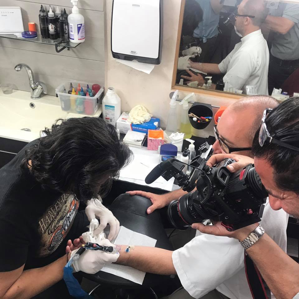 Our priest getting his first tattoo.